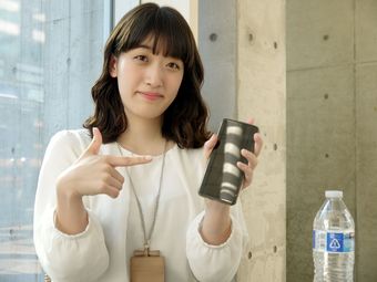 茨城新聞をおすすめするようにスマートフォンを指さす女性