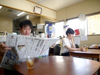 茨城新聞を紙で読む男性と茨城新聞電子版をスマホで読む女性