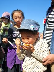 焼き上がった創作たこ焼きをおいしそうに食べる女児=ひたちなか市和田町