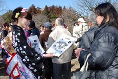 観光客に記念品を配る水戸の梅大使(左)=水戸市常磐町の偕楽園東門付近