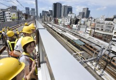 公開された東北縦貫線の高架橋の線路から、隣接するJR神田駅(右)を見下ろす地元の人たち=12日午前、東京都千代田区