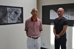 独自の視点のモノクロ表現で写した作品を展示する島利宣さん(右)と萩谷靖さん=水戸市見川町