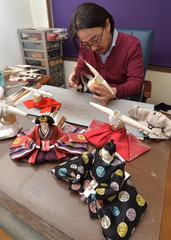 女びなにはかまを着せる小佐畑孝雄さん=城里町阿波山