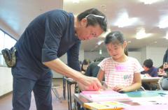 参加した子どもに色の塗り方を教える原高史さん(左)=常陸太田市東二町