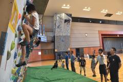 「夏休みクライミング体験教室」でボルダリングの壁に取り付く児童(手前)ら=鉾田市当間の鉾田総合公園体育館