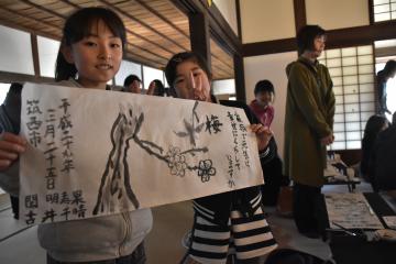 ふすま絵の下張り用の和紙に梅とメッセージを書き上げる参加者=水戸市三の丸