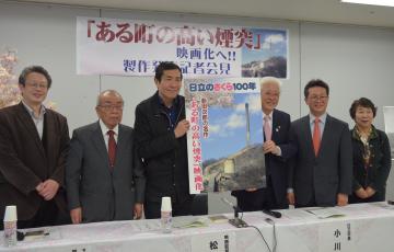 「ある町の高い煙突」の映画化を発表する松村克弥監督(左から3人目)と日立市の小川春樹市長(同4人目)など関係者=日立市幸町