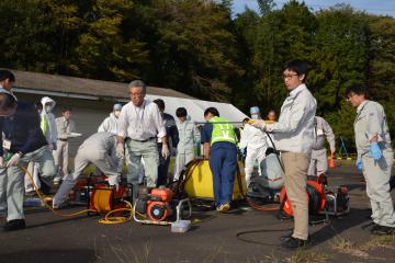 車両消毒に使用する「動力噴霧器」を体験する参加者ら=水戸市上国井町