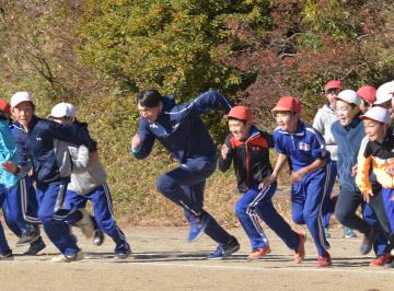 子どもたちと走り、世界の速さを体感させる高平慎士さん(中央)=石岡市立林小学校