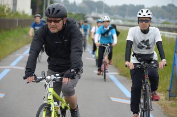 自転車専用道の路面標示に従い霞ケ浦湖畔を走る参加者たち=土浦市湖北