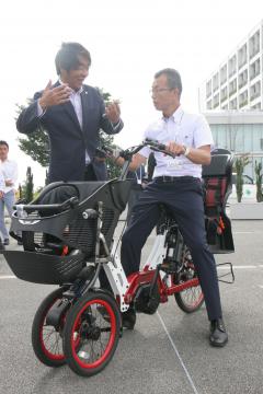 電動三輪車「トヨダトライク」の説明を受けるつくば市職員(右)=同市研究学園