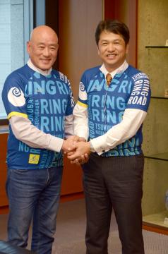 大井川和彦知事(右)と懇談後、本県のサイクルジャージー姿で握手する台湾の自転車メーカー・ジャイアントの羅祥安前社長=知事応接室
