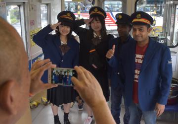 国際交流列車で、駅員になりきり記念撮影する参加者=龍ケ崎市内