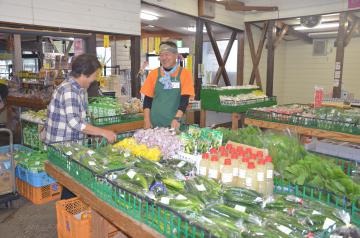 野菜が並ぶ前で出荷した農家と会話する谷津安男店長(右)=城里町御前山