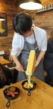 料理にラクレットチーズをかける店員=守谷市松ケ丘の「Cheese　Cheers　Cafe」
