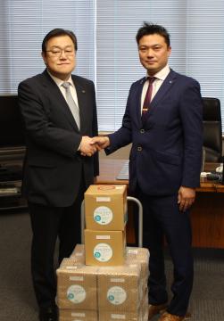神栖市に消毒液50リットルを寄贈したかしま青年会議所の小田智之理事長(右)=同市役所