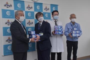 かすみがうら市の坪井透市長(左)から医療機関関係者にマスクが寄贈された=同市役所