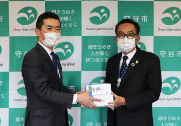 松丸修久守谷市長(右)にマスクを手渡すアサヒビール茨城工場の松井宏樹総務部長=同市役所