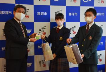 先崎光市長(左)に手作りのマスクを手渡す友部ひよりさん(中央)と颯大さん=那珂市役所