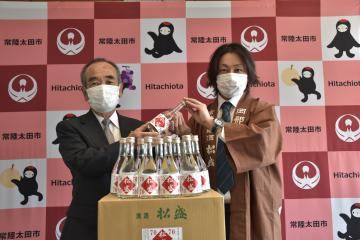 大久保太一市長(左)に高濃度アルコール製品を手渡す岡部彰博専務=常陸太田市役所