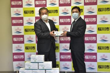 桜川市にマスクを寄贈した梅内勇一さん(右)=同市役所