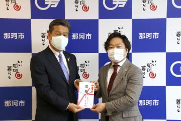 先崎光市長(左)に目録を手渡す「アフターフィット」の谷本貫造代表取締役=那珂市役所