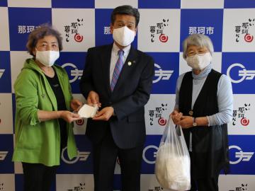 先崎光市長(中央)に手作りマスクを手渡す大友悦子さん(左)と富張澪子さん=那珂市役所