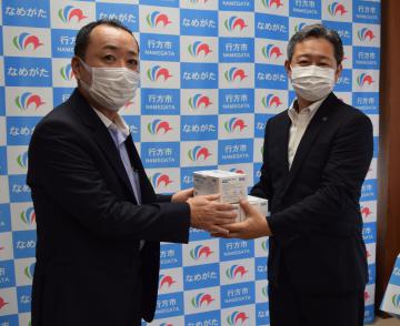 鈴木周也行方市長(右)にマスクを手渡す藤崎社長=行方市役所麻生庁舎