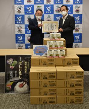 パックご飯500食分を寄贈した「茨城農栄」の金久保正義社長(左)と坂東市の木村敏文市長=同市役所