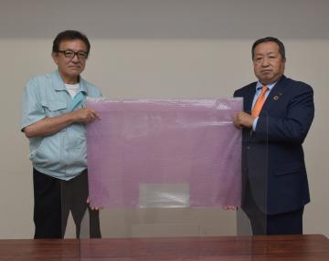 鉾田市に透明の仕切り板を贈呈したカブトプラテクの吉村茂則営業部専任部長(左)=鉾田市役所