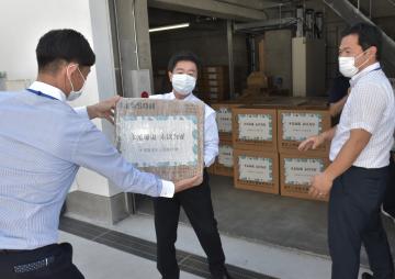 重慶市から送られた医療用資機材が入った段ボール箱を倉庫に運び入れる高橋靖市長(中央)ら=水戸市役所