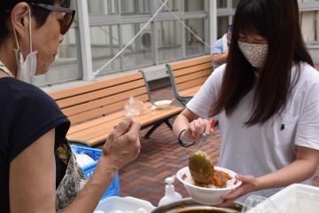 「にこにこ食堂」スタッフが作ったカレーを自分で盛り付ける大学生(右)=水戸市文京