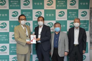 新型コロナウイルス対策として、松丸修久守谷市長(左)に寄付金を手渡す同市災害対策協力会の役員=同市役所
