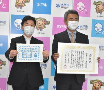 感染予防ステッカーを手に持つ水戸市の高橋靖市長(左)と、市から感謝状を贈られたサトー茨城支店の本多憲司支店長=同市役所