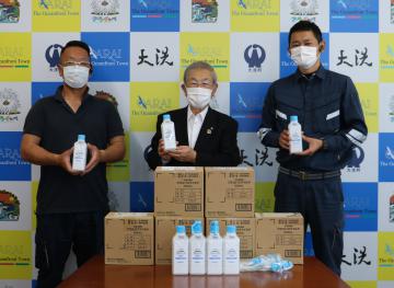 小谷隆亮町長(中央)に消毒液を寄贈したクロサワクリーンサービスの小林和浩取締役(右)ら=大洗町役場