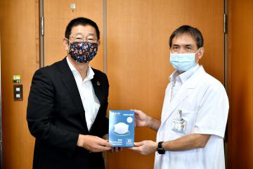 島居徹病院長(右)に医療用マスクを手渡す近藤慶一副市長=笠間市鯉淵