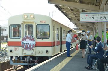 ヘッドマーク付きの車両の前で式典を開く関係者たち=龍ケ崎市の関東鉄道竜ケ崎線竜ケ崎駅