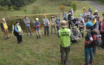 助川山市民の森内の「石の池」で地層などの説明を聞く参加者=日立市諏訪町