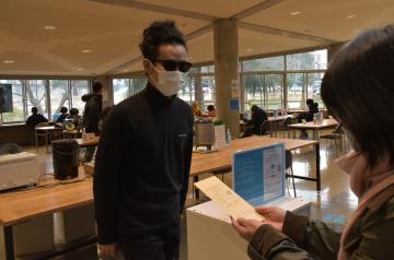 藝大食堂の「値段を付けないランチ」。支払う金額を明記した封筒をスタッフに渡す学生(中央)=取手市小文間の東京芸術大