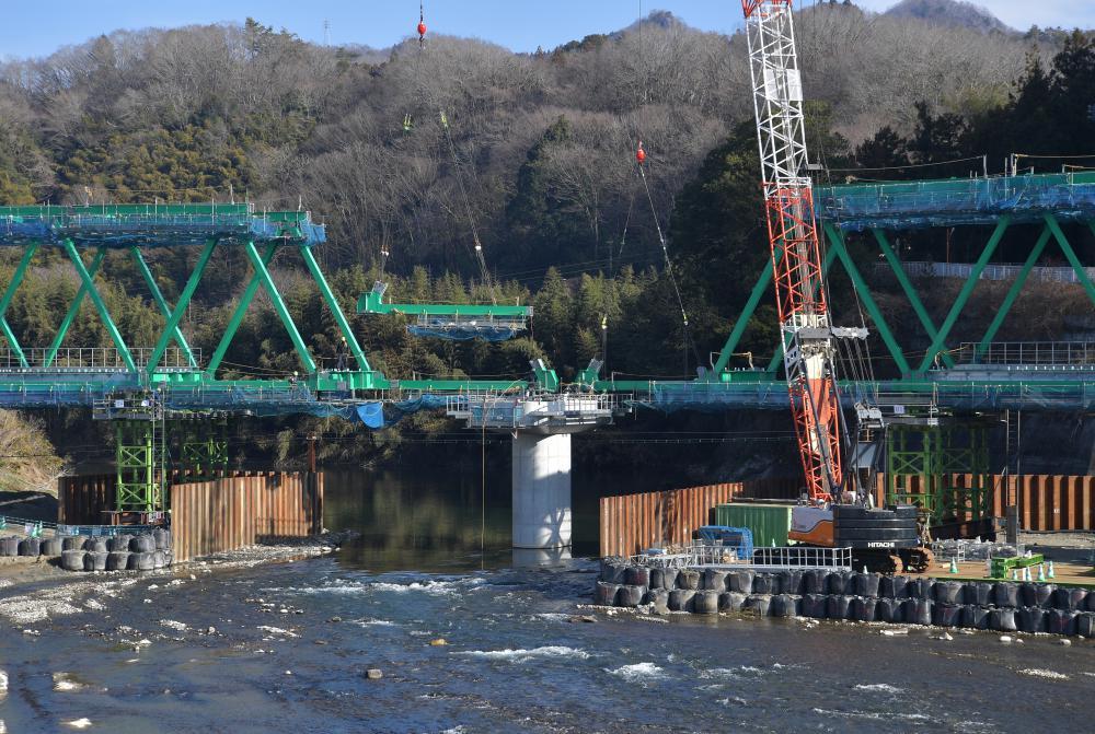 復旧工事が進む水郡線の鉄橋。両岸から組み立てていた橋桁が一つにつながった=7日午前、大子町久野瀬