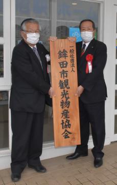 鉾田市観光物産協会の開所式で看板を掲げる荒野吉生会長(左)と岸田一夫市長=同市下太田