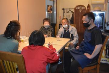 カレーを食べる子どもを見守るアイズカフェの石田健一さん(右)と民生委員の谷田部典子さん(左)=ひたちなか市表町