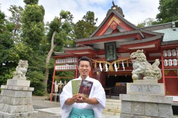 助川鹿嶋神社オリジナル御朱印帳を手に笑顔で神社への思いを語る臼井強禰宜=日立市鹿島町