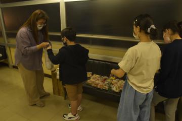 NPO法人の森美智子理事長(左)から配布用の食品を受け取る子どもたち。食品は寄付や購入で賄われている=つくば市内