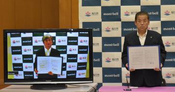 オンライン中継で連携協定書を取り交わした、桜川市の大塚秀喜市長とモンベルの辰野勇会長(左)=同市大和庁舎