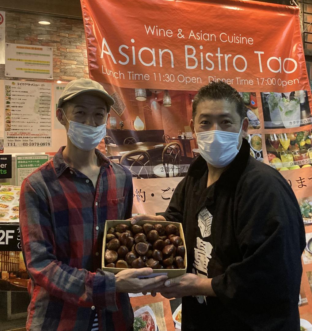 飲食店店主に笠間の栗を手渡す馬場万作さん(右)=都内・池袋(馬場さん提供)