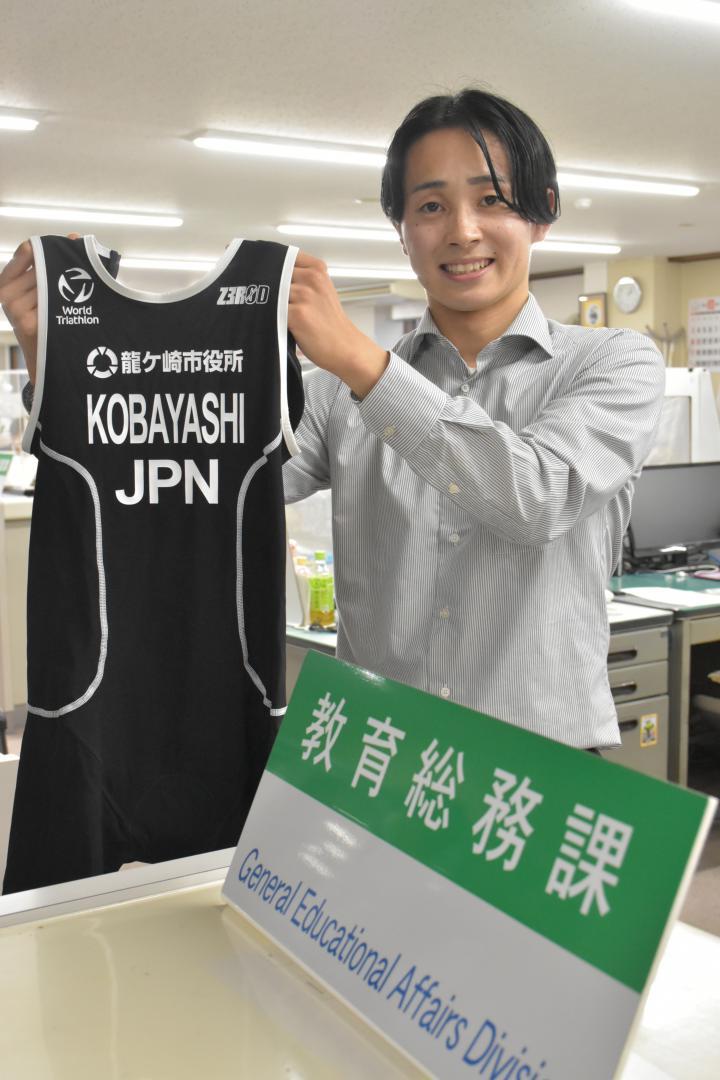 「龍ケ崎市役所」と入ったレースウエアを手に意気込みを語る小林竜馬さん=同市役所