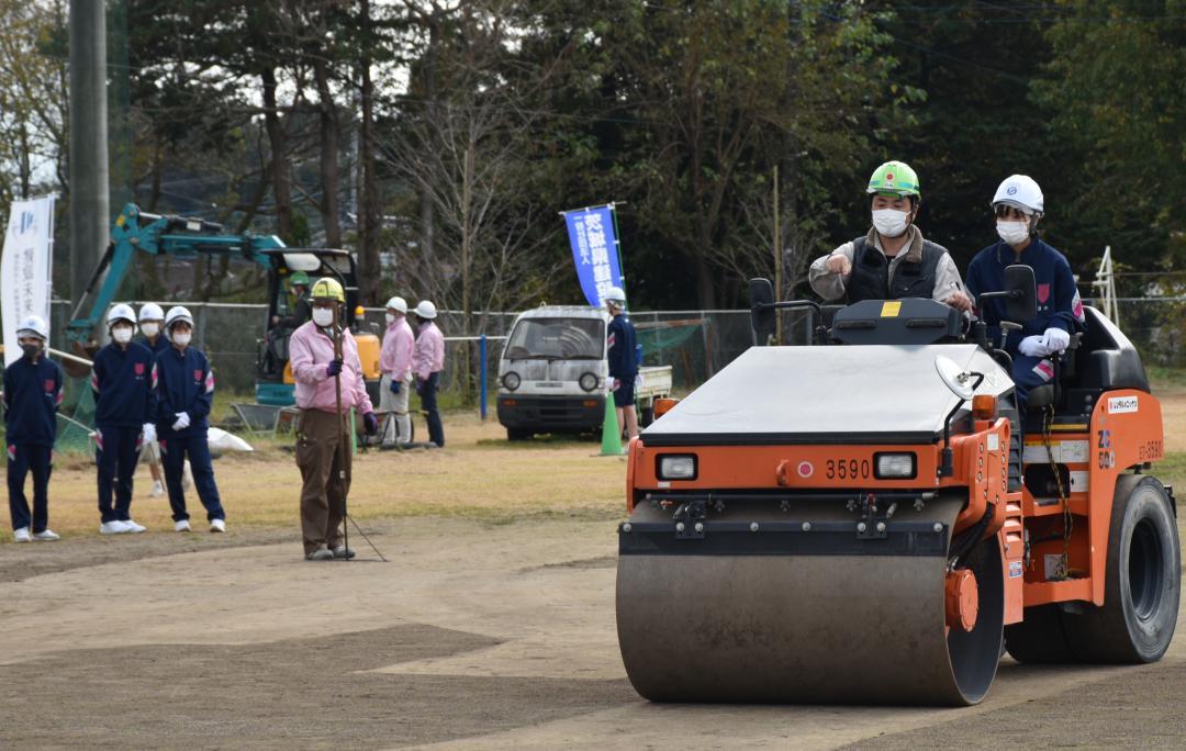 転圧ローラーに乗り土を固める作業を学ぶ生徒=常陸大宮市石沢の市立二中グラウンド