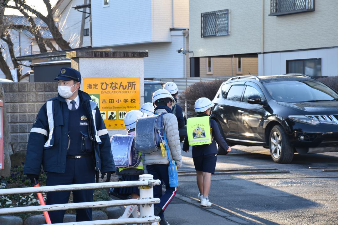 水戸市立吉田小の校門前では警察官が送迎車を誘導しながら登校児童を見守った=18日午前7時50分ごろ、同市元吉田町
