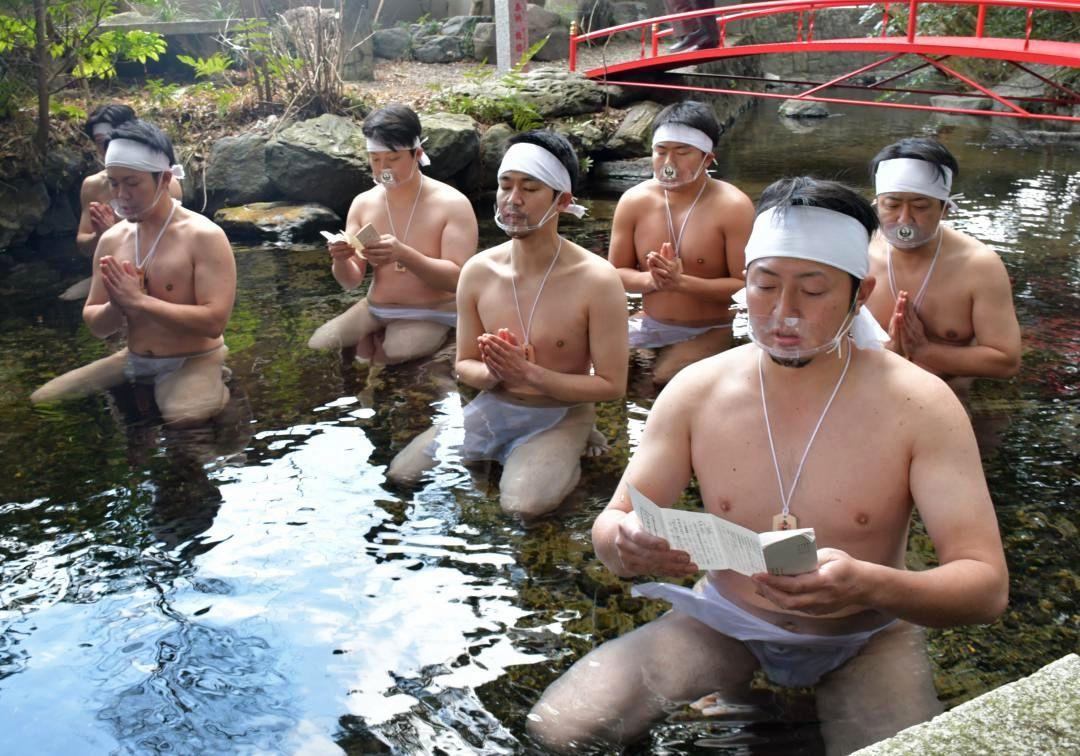 境内の泉に入り、祝詞を上げる神職たち=日立市水木町の泉神社
